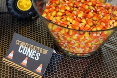 a bowl filled with candy corn on top of a table next to a construction sign