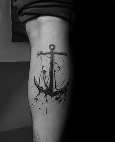 a black and white photo of an anchor tattoo on the left arm with watercolor splatters