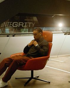 a man sitting in an orange chair with his hand on his chin