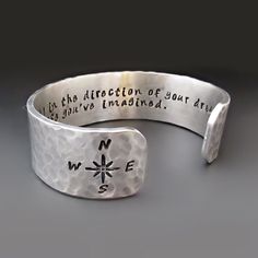 "Inspire someone to move forward with purpose and follow their dreams with this silver Directions of your Dreams Bracelet. The inside of the cuff is hand stamped with the following quote by Henry David Thoreau: Go confidently in the direction of your dreams. Live the life you've imagined. The outside edge(s) of the cuff can be stamped with YOUR CHOICE OF UP TO TWO IMAGES (SEE PHOTOS) If no image(s) are indicated during the checkout process a compass rose symbol will be added to the outside edge. Cheap Hand-stamped Bangle Cuff Bracelet, Cheap Hand-stamped Bangle Bracelets, Metal Stamped Jewelry Bracelets, Luxury Etched Bracelets As A Gift, Luxury Stamped 925 Cuff Bracelet For Anniversary, Cheap Hand Stamped Cuff Bracelet As Gift, Cheap Hand Stamped Cuff Bangle Bracelet, Cheap Hand Stamped Bracelets For Gifts, Cheap Hand Stamped Bracelets