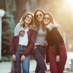 three women are posing for the camera with their arms around each other and one is wearing sunglasses