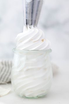 a glass jar filled with whipped cream on top of a white countertop next to a striped towel