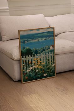 a white couch sitting next to a painting on top of a hard wood floor