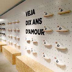 there are many pairs of shoes hanging on the wall in this room with wooden benches