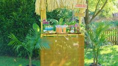 a tiki bar in the middle of a yard with plants and flowers on it