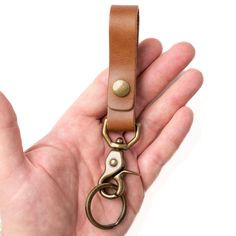 a hand holding a brown leather key chain