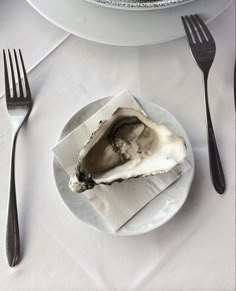 an oyster on a plate with silverware next to it