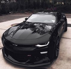 a black chevrolet camaro is parked in the driveway