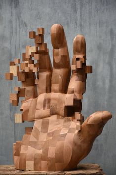 a wooden sculpture made to look like a hand with multiple blocks on it's palm