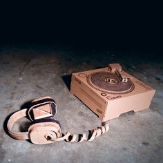 a cardboard box sitting on the ground next to a pair of headphones that are tied up