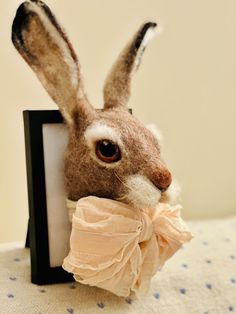 a stuffed rabbit with a bow tie on it's head sitting next to a frame