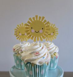 cupcakes with white frosting and sun decorations on top are sitting on a plate