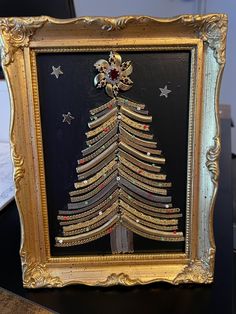 a christmas tree made out of books in a gold frame on a black table top