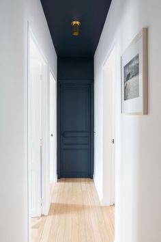 an empty hallway with blue walls and white trim on the doors, wood flooring