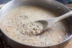 a wooden spoon in a saucepan filled with meat and gravy on a table