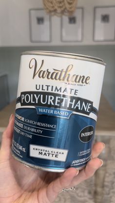 a person holding up a can of blue water based paint in front of a kitchen counter