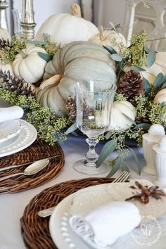 the table is set with white pumpkins and greenery