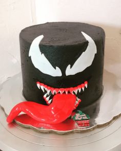 a black cake with white teeth and fangs on it's face, sitting on a silver platter