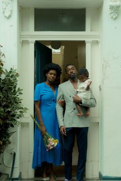 a man and woman holding a baby in front of a doorway