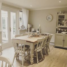 a dining room table with chairs and a clock on the wall