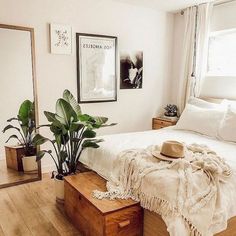 a bedroom with a bed, mirror and plants on the floor in front of it