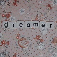 the word dream spelled out with scrabble letters on a floral wallpaper background