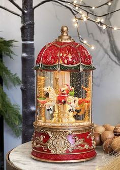 a christmas carousel with lights and ornaments around it on a table next to some nuts