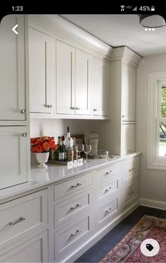 a kitchen filled with lots of white cupboards and counter top next to a window