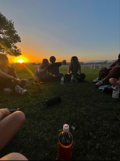 group of people sitting in the grass at sunset