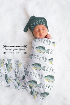 a newborn baby wearing a green hat and sleeping on a white blanket