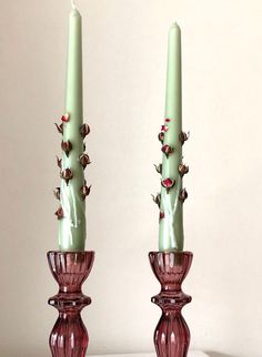 two green candles sitting next to each other on a table