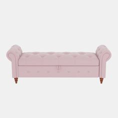 an upholstered pink couch with wooden legs and buttons on the armrests