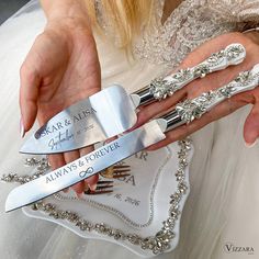 the bride is holding her wedding cake knifes with their names engraved on them as they hold each other's knives