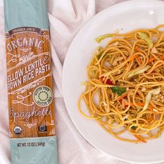 a white plate topped with spaghetti next to a bottle of organic brown rice pasta sauce