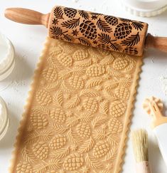 a wooden rolling pin with pineapples carved on it next to other decorations and tools