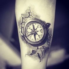 a black and white photo of a compass tattoo on the right leg, with water splashing all over it