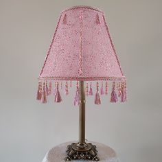 a pink table lamp with tassels on it