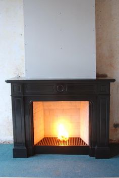 a fireplace with a fire burning in it's mantle next to a white wall