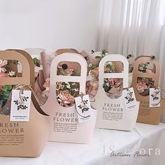 four bags with flowers on them are sitting on a white tablecloth and there is also a sign that says fresh flower