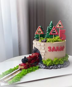 a birthday cake with a train on the top and trees in the middle, along with other decorations