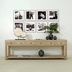 a wooden table sitting in front of a wall with pictures on it