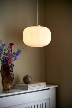 a lamp that is on top of a table next to a vase with flowers in it