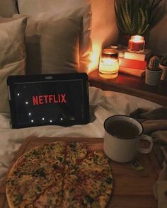 a pizza sitting on top of a wooden cutting board next to a cup of coffee