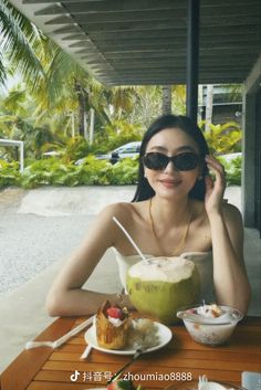 a woman wearing sunglasses sitting at a table with food and drinks in front of her