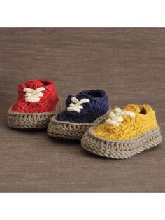 three crocheted baby shoes sitting on top of a gray floor next to each other