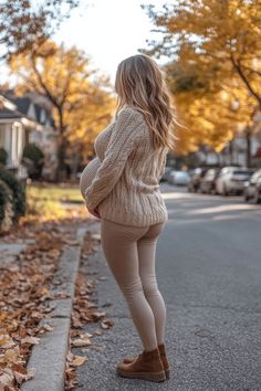 Pregnant woman standing on a tree-lined street in autumn, wearing a cozy beige sweater and beige leggings, surrounded by fallen leaves. Maternity Outfits For Winter, Easy Maternity Outfits, Early Maternity Outfits, Bump Style Winter, Cool Maternity Outfits, Maternity Leggings Outfit, Cute Maternity Clothes, Best Maternity Leggings