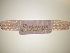 a pink belt with the word survive on it and gold sequins around the waist