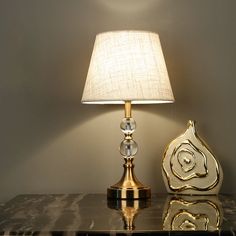 a lamp on a table next to a vase with a flower in it and a marble base