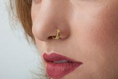 a close up of a woman's nose with a gold nose ring on it