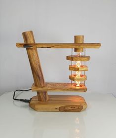 a wooden table lamp with several lights on it and a white wall in the background